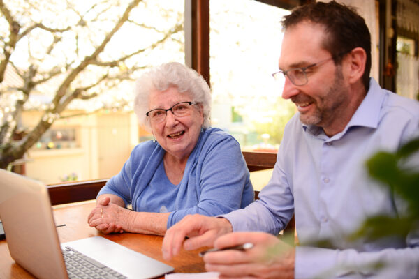 mature man helping elderly senior woman at home with advanced estate planning